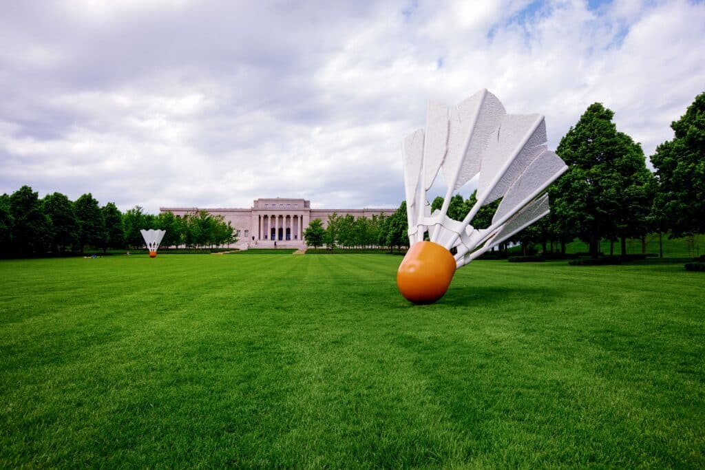 volant de badminton géant sur une pelouse avec un bâtiment du Nelson Atkins Art Museum au fond