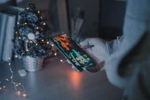main tenant un smartphone avec sapin de noël dans le fond